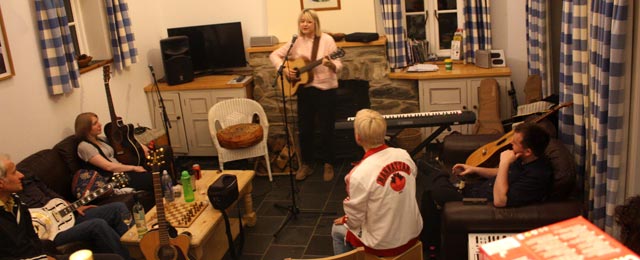 Catherine Rudie plays a song for the other songwriters in the living room of the cottage.